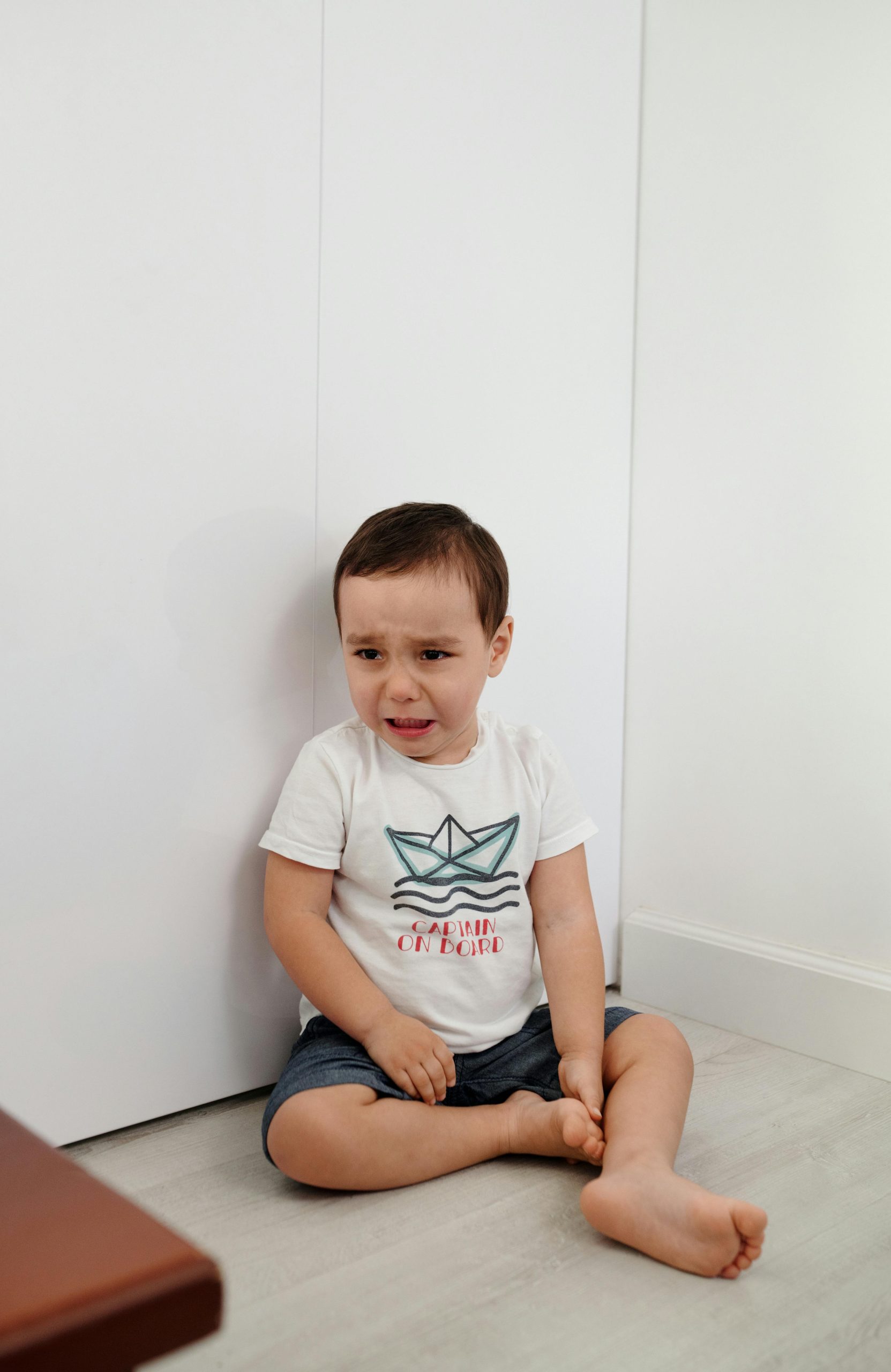 very young little boy crying sitting on the floor
