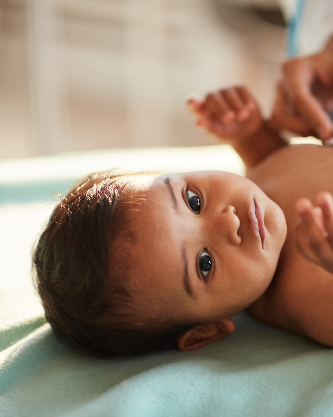 baby lying down on doctor's bed about to have a vaccination