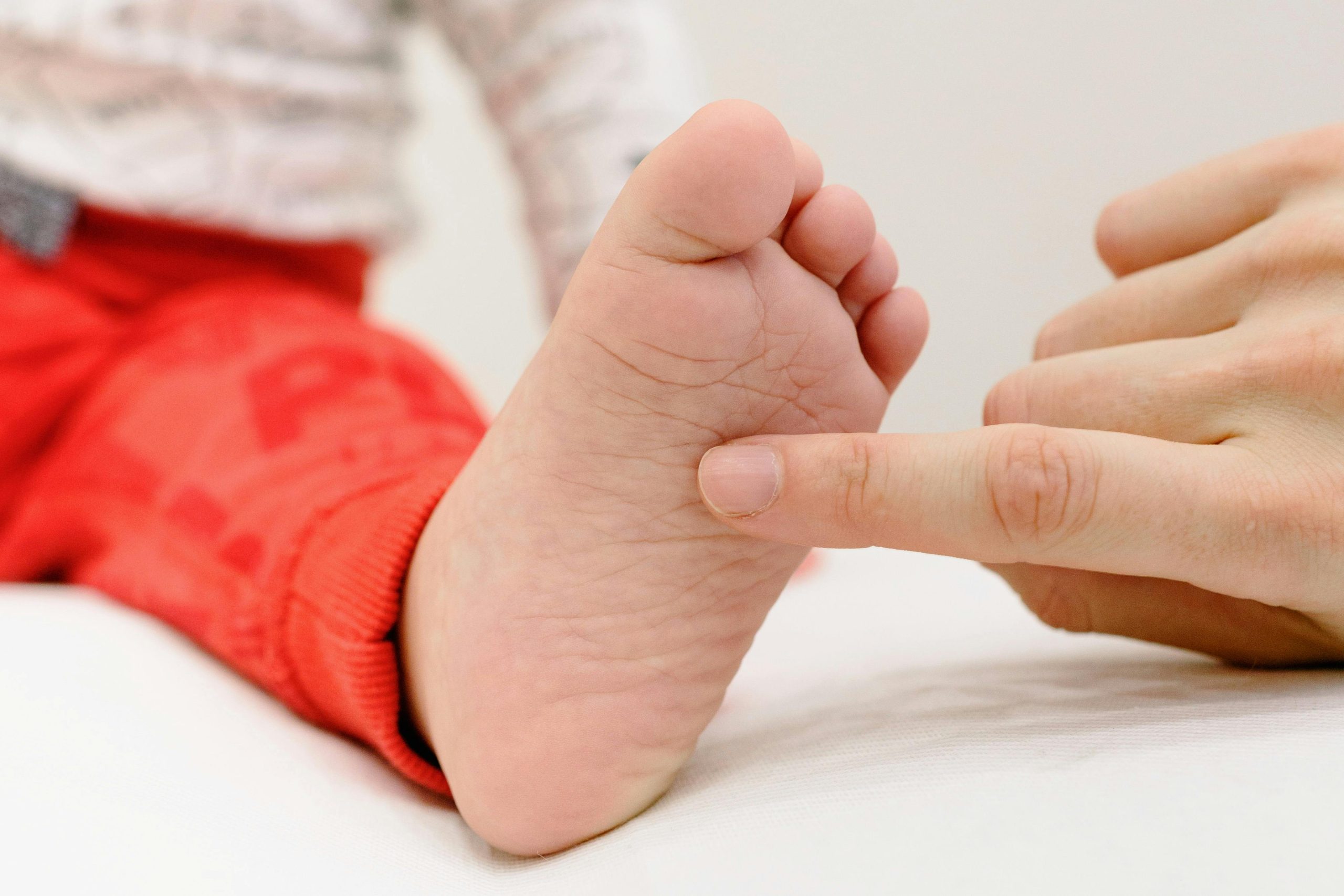 adult physiotherapist looking at and touching child's foot